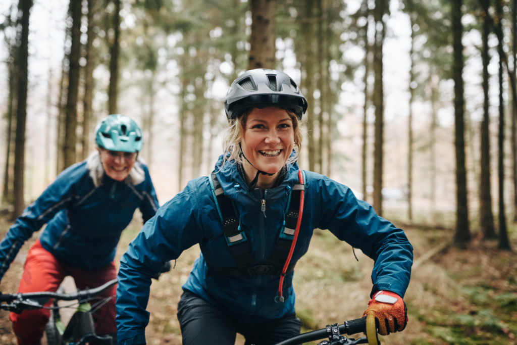 Lachende Dame auf dem Mountainbike unterwegs auf einem Flowtrail.