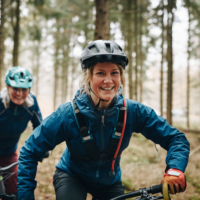 Lachende Dame auf dem Mountainbike unterwegs auf einem Flowtrail.