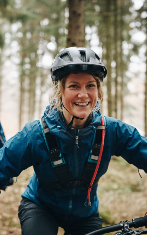 Lachende Dame auf dem Mountainbike unterwegs auf einem Flowtrail.