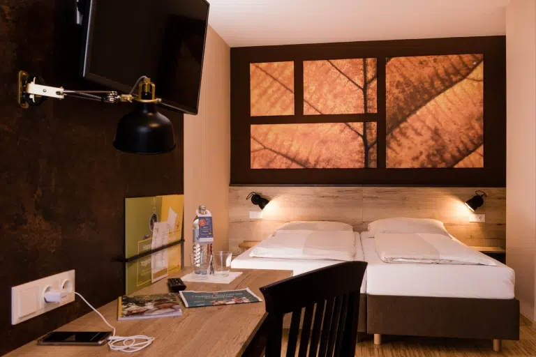 Sie sehen ein Doppelbett in einem Doppelzimmer im JUFA Hotel Fürstenfeld. Der Ort für erfolgreiches Training in ungezwungener Atmosphäre für Vereine und Teams.