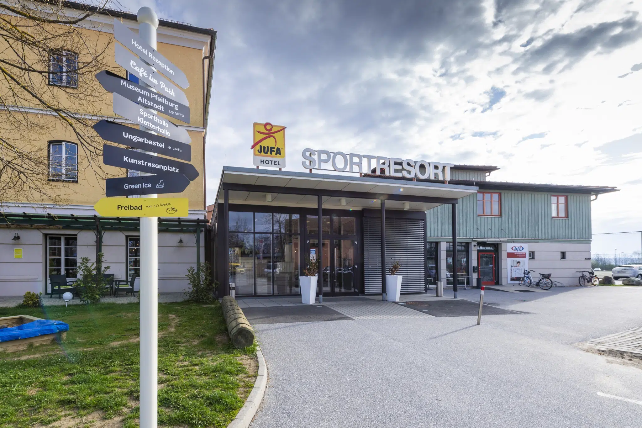 Sie sehen eine Außenansicht vom JUFA Hotel Fürstenfeld mit dem Hoteleingang. JUFA Hotels bietet Ihnen den Ort für erfolgreiches Training in ungezwungener Atmosphäre für Vereine und Teams.