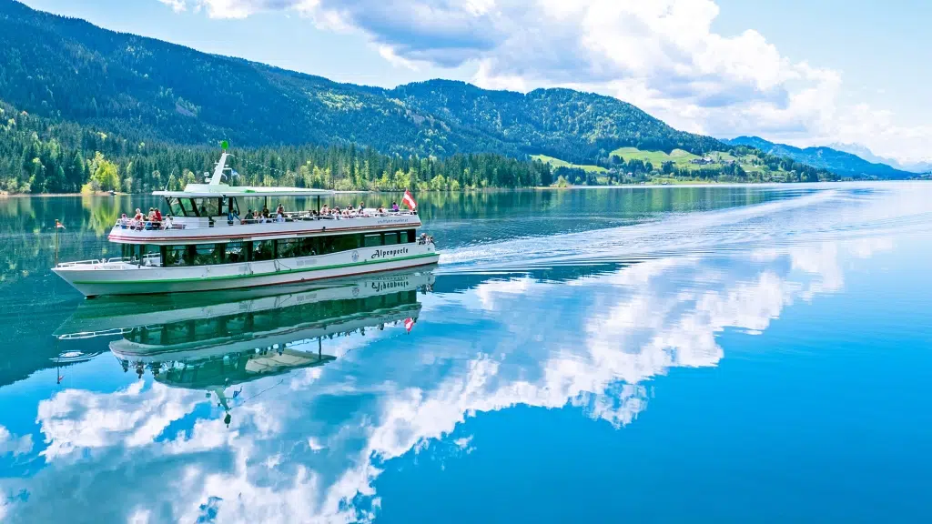 Sie sehen die "Alpenperle" am Weissensee fahren.