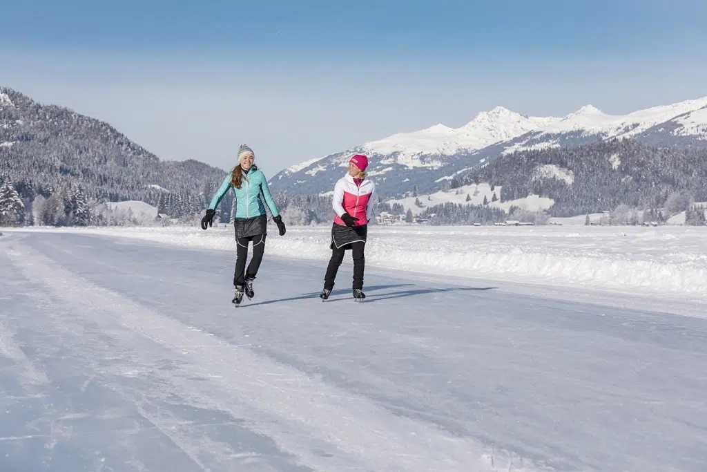 Ihr seht zwei Personen beim Eislaufen am Weissensee.