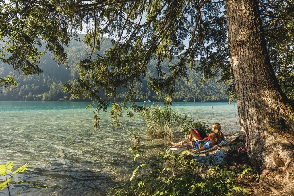 Sie sehen zwei Personen auf einer Schaukel am Weissensee.