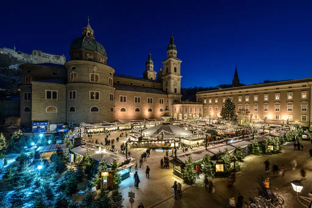 Ihr seht den Christkindlmarkt am Salzburger Residenzplatz mit dem Dom im Hintergrund.