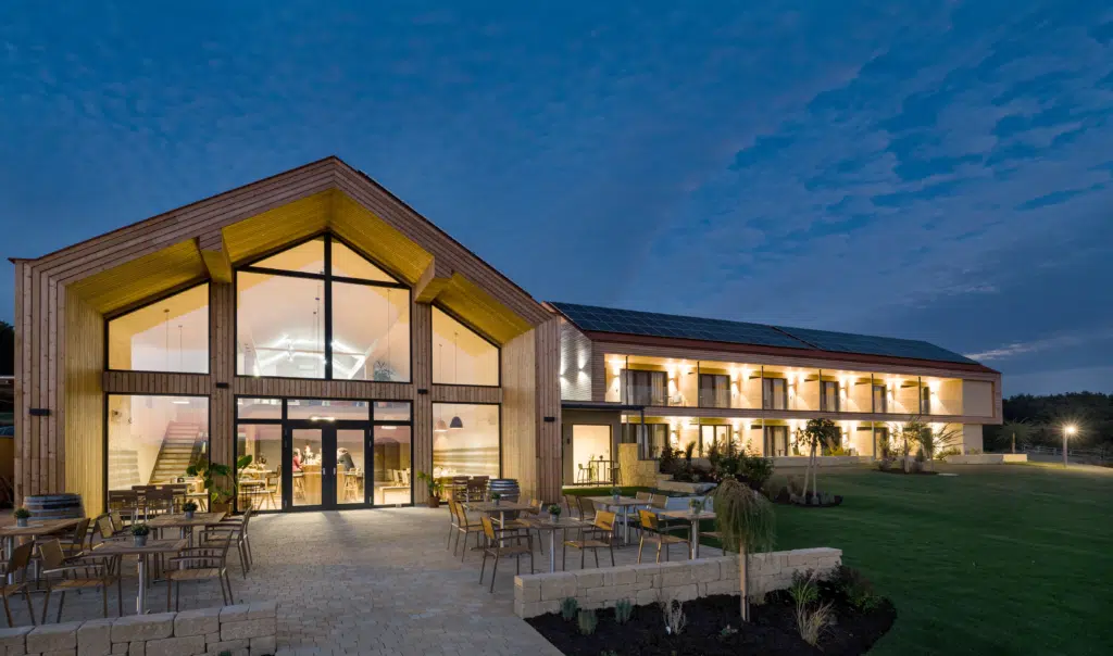 Außenansicht vom EventArium am JUFA Hotel Neutal – Landerlebnis mit Terrasse am Abend. JUFA Hotels bietet Ihnen den Ort für erlebnisreichen Natururlaub für die ganze Familie.