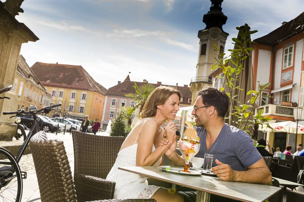 Ihr seht einen Mann und eine Frau beim Eis essen am Hauptplatz von Bad Radkersburg ganz in der Nähe vom JUFA Hotel Bad Radkersburg.