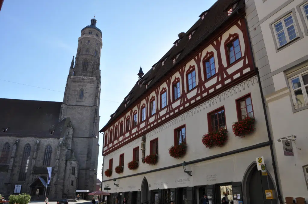 Ihr seht ein altes Haus und eine Kirche als Baudenkmäler in Nördlingen. JUFA Hotels bietet erholsamen Familienurlaub und einen unvergesslichen Winter- und Wanderurlaub.