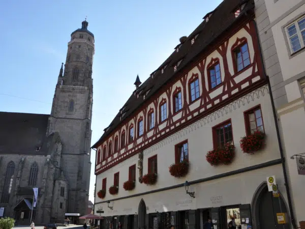 Ihr seht ein altes Haus und eine Kirche als Baudenkmäler in Nördlingen. JUFA Hotels bietet erholsamen Familienurlaub und einen unvergesslichen Winter- und Wanderurlaub.