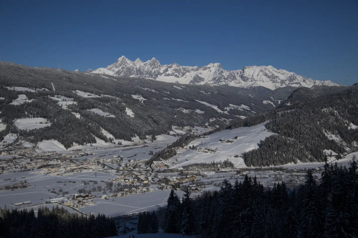 Ihr seht einen schönen Ausblick von oben auf Altenmarkt vor dem Dachsteinmassiv in der Nähe vom JUFA Hotel Altenmarkt***.