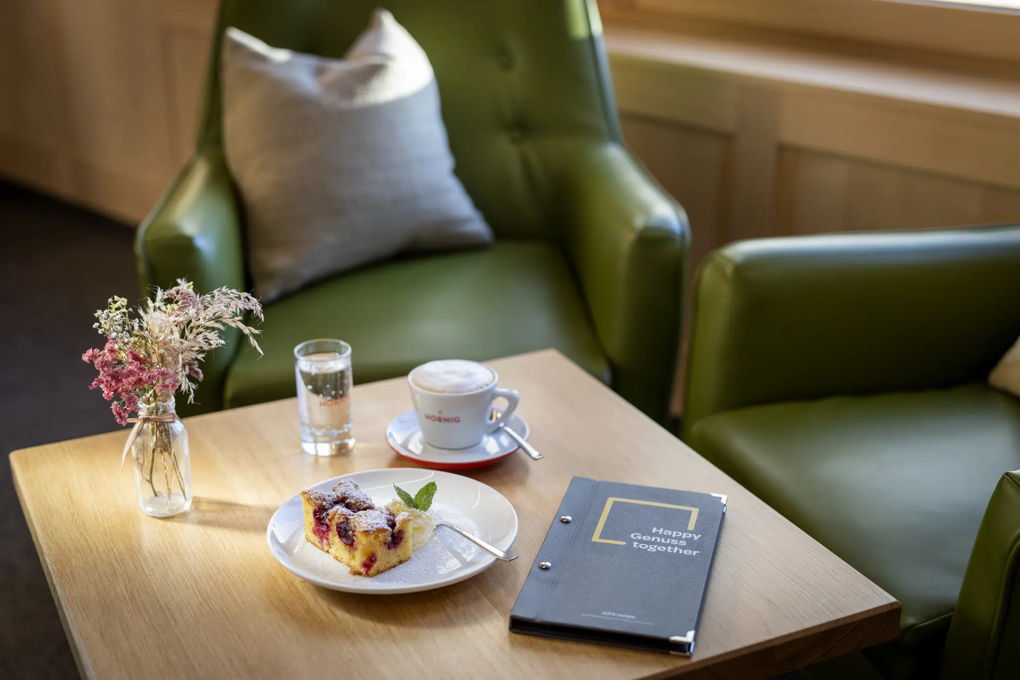 Ihr einen Tisch mit Kaffee, Kuchen und Blumen im JUFA Hotel Laterns-Klangholzhus***s. Der Ort für einen abwechslungsreichen Winterurlaub für die ganze Familie mit erholsamen Urlaubstagen.