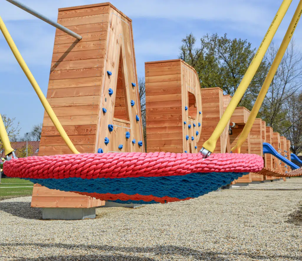 Ihr seht den Spielbereich Fluidum mit Boulderwänden und Schaukel im Außenbereich der Parktherme Bad Radkersburg.