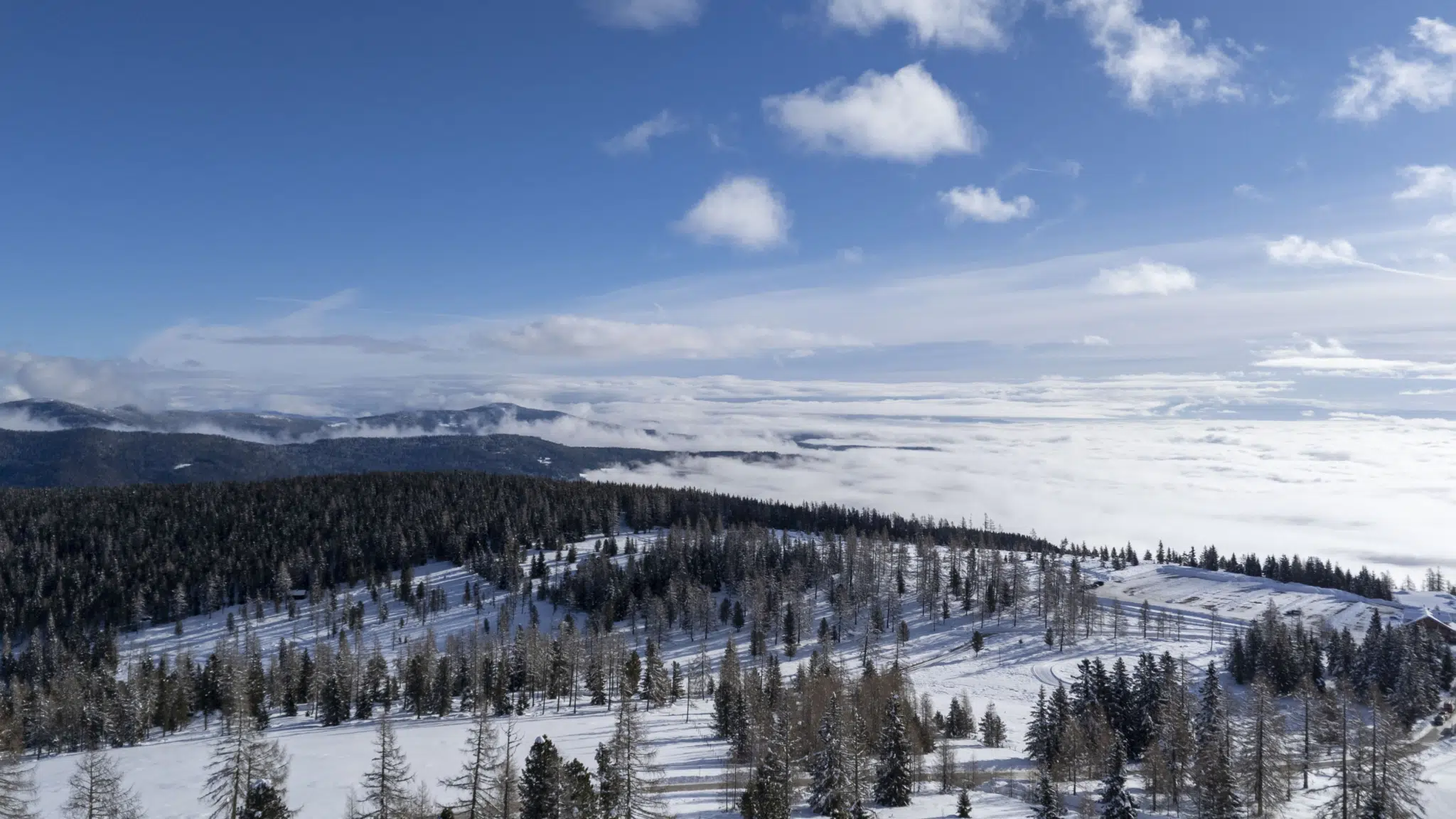 Ihr seht eine Drohnenaufnahme vom Skigebiet Hochrindl/Nockberge im Winter bei traumhaft schönem Wetter. JUFA Hotels bietet einzigartige Familienurlaube und unvergessliche Winter- und Sommerurlaube im JUFA Hotel Hochrindl***.