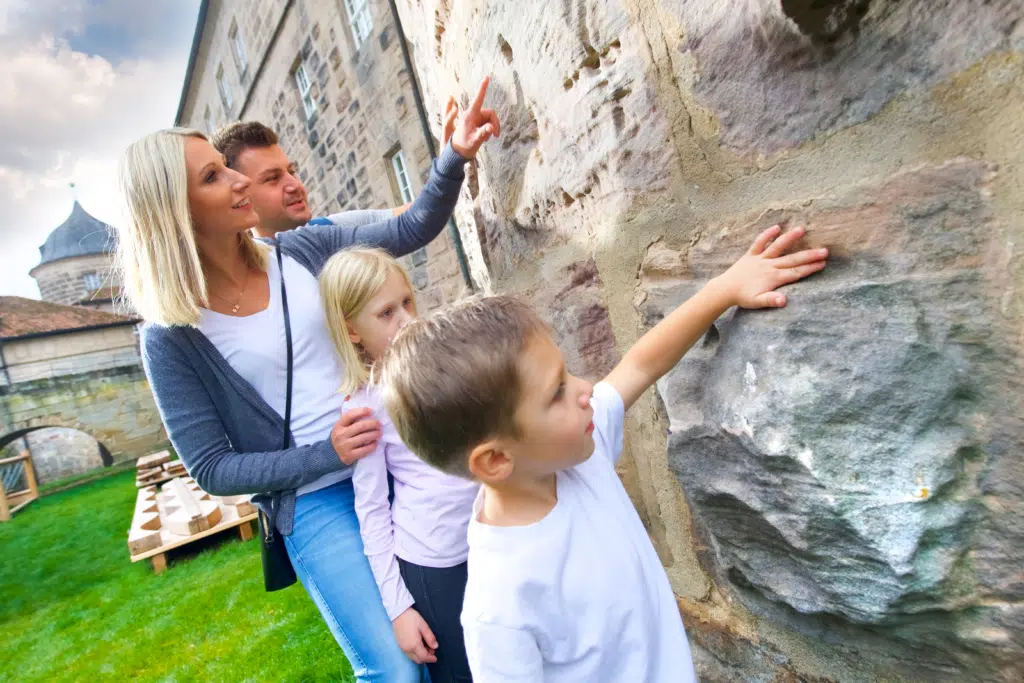 Ihr seht eine Familie an der Festungsmauer im JUFA Hotel Festung Rosenberg Kronach***s. Der Ort für kinderfreundlichen und erlebnisreichen Urlaub für die ganze Familie.