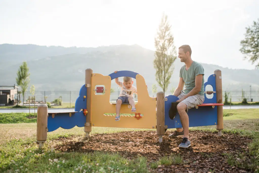 Ihr seht eine Familie im Outdoorspielbereich am JUFA Hotel Stubenbergsee. Der Ort für kinderfreundlichen und erlebnisreichen Urlaub für die ganze Familie.