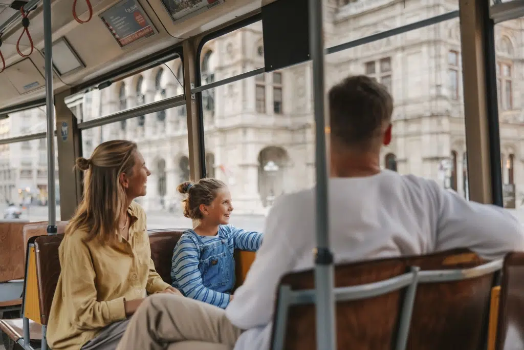 Ihr seht eine Familie in einer Straßenbahn in Wien. JUFA Hotels bieten den Ort für erlebnisreichen Städtetrip für die ganze Familie.