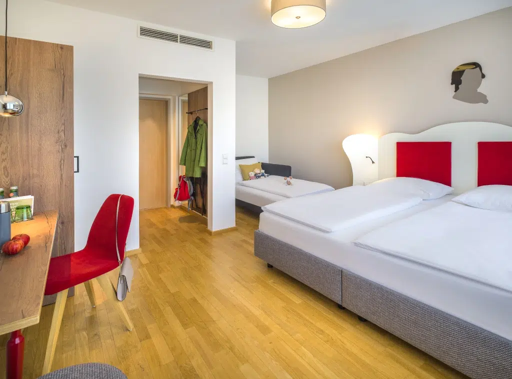 Ihr seht ein FF3 Zimmer mit Betten im JUFA Hotel Salzburg City. Der Ort für erholsamen Familienurlaub und einen unvergesslichen Winter- und Wanderurlaub.