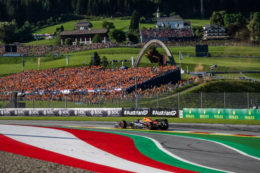 Ihr seht ein Bild vom Formel 1 Rolex Großen Preis von Österreich am Red Bull Ring in Spielberg mit dem Formel 1 Auto von Max Verstappen und zahlreichen Zuschauer im Hintergrund.