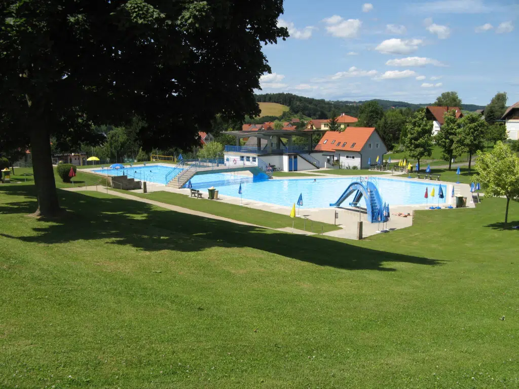 Ihr seht das Freibad Gnas mit großer Liegewiese zum Entspannen. JUFA Hotels bieten erholsamen Familienurlaub und einen unvergesslichen Winter- und Wanderurlaub.