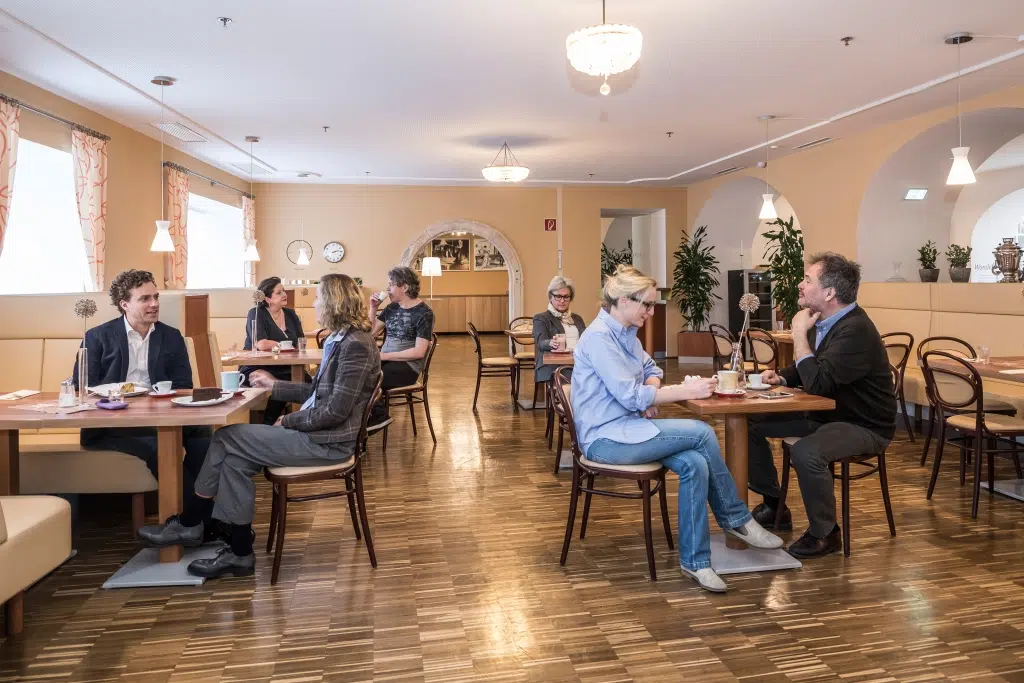 Ihr seht Gäste im gemütlichen Wiener Café im JUFA Hotel Wien City. Der Ort für erlebnisreichen Städtetrip für die ganze Familie und der ideale Platz für euer Seminar.