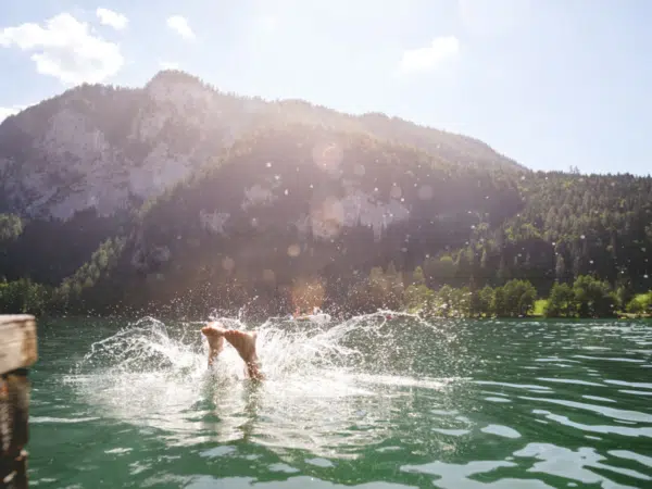 Ihr seht einen Sprung in den Gleinkersee mit Bergblick – unweit vom JUFA Hotel Pyhrn-Priel.