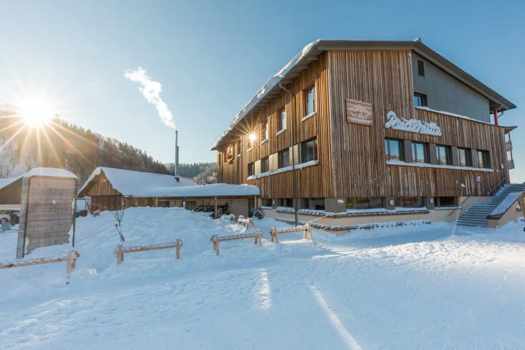 Ihr seht die Aussenansicht vom JUFA Hotel Annaberg***s und Reidlhütte im Winter. Der Ort für erholsamen Familienurlaub und einen unvergesslichen Winter- und Wanderurlaub.