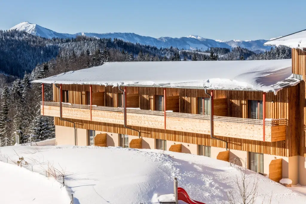 Ihr seht eine Außenansicht vom JUFA Hotel Annaberg***s mit Balkonen und Zimmerterrassen im Winter. JUFA Hotels bietet erholsamen Familienurlaub und einen unvergesslichen Winterurlaub.