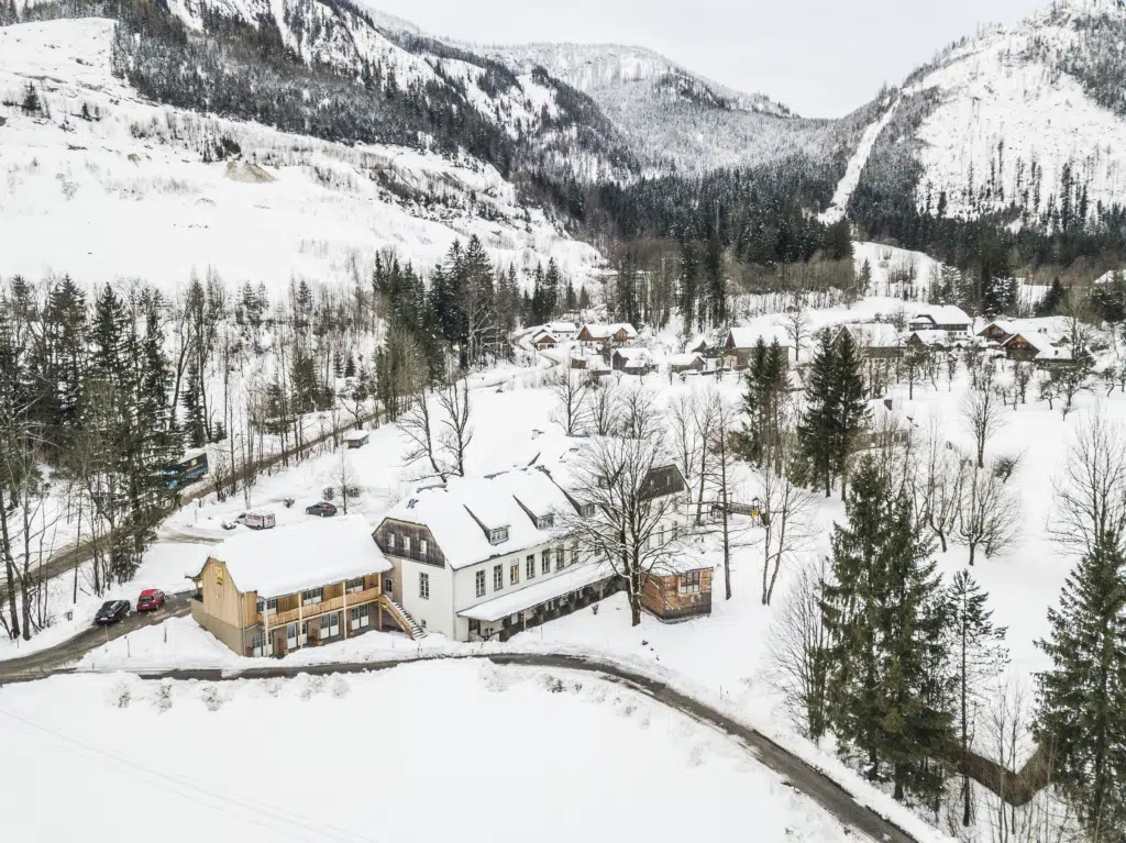 Ihr seht eine Außenansicht vom JUFA Hotel Grundlsee*** mit Schnee im Winter. JUFA Hotels bietet erholsamen Familienurlaub und einen unvergesslichen Winterurlaub.