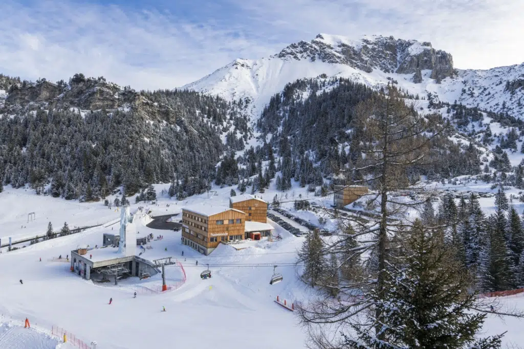 Sie sehen eine Außenansicht vom JUFA Hotel Malbun – Alpin-Resort*** mit Skipiste im Winter. JUFA Hotels bietet erholsamen Familienurlaub und einen unvergesslichen Winterurlaub.