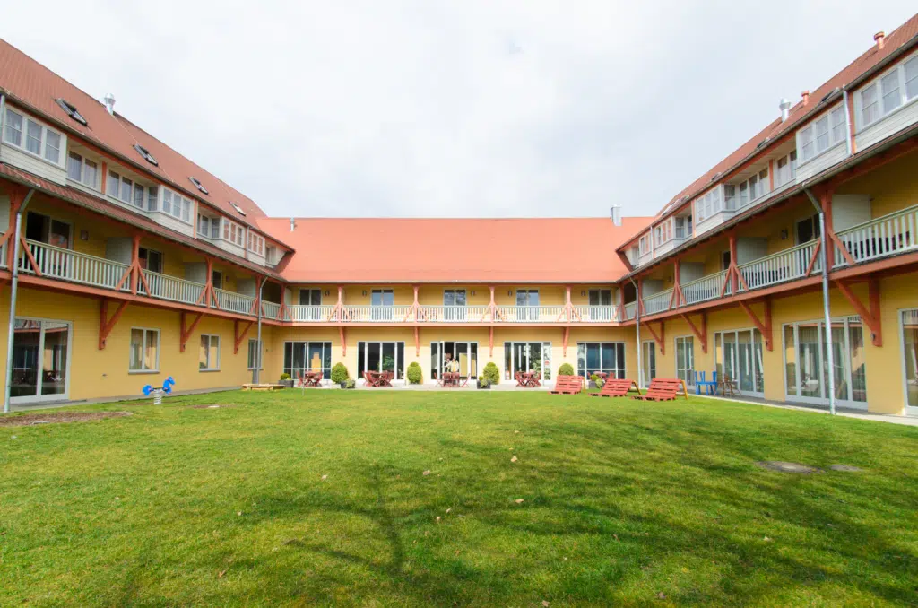 Ihr seht eine Aussenansicht mit Terrasse und Garten im Sommer vom JUFA Hotel Nördlingen***. Der Ort für kinderfreundlichen und erlebnisreichen Urlaub für die ganze Familie.