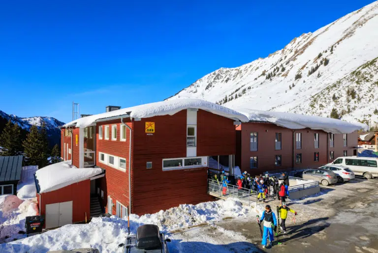 Ihr seht eine Hotelansicht vom JUFA Hotel Planneralm – Alpin-Resort mit Gästen im Winter. JUFA Hotels bietet erholsamen Familienurlaub und einen unvergesslichen Winterurlaub.