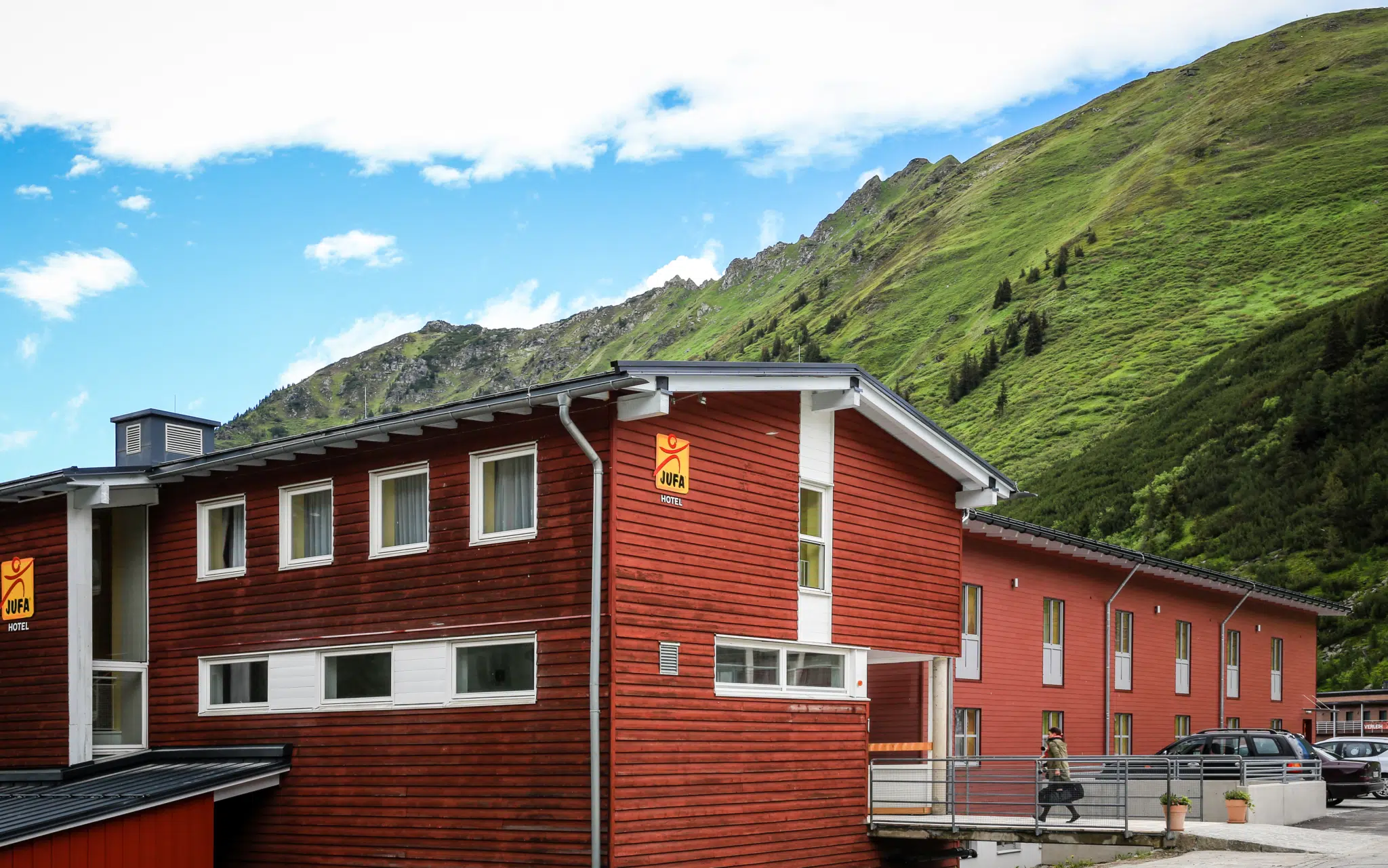 Aussenansicht vom JUFA Hotel Planneralm - Alpin-Resort mit Parkplatz im Sommer. JUFA Hotels bieten erholsamen Familienurlaub und einen unvergesslichen Winter- und Wanderurlaub.