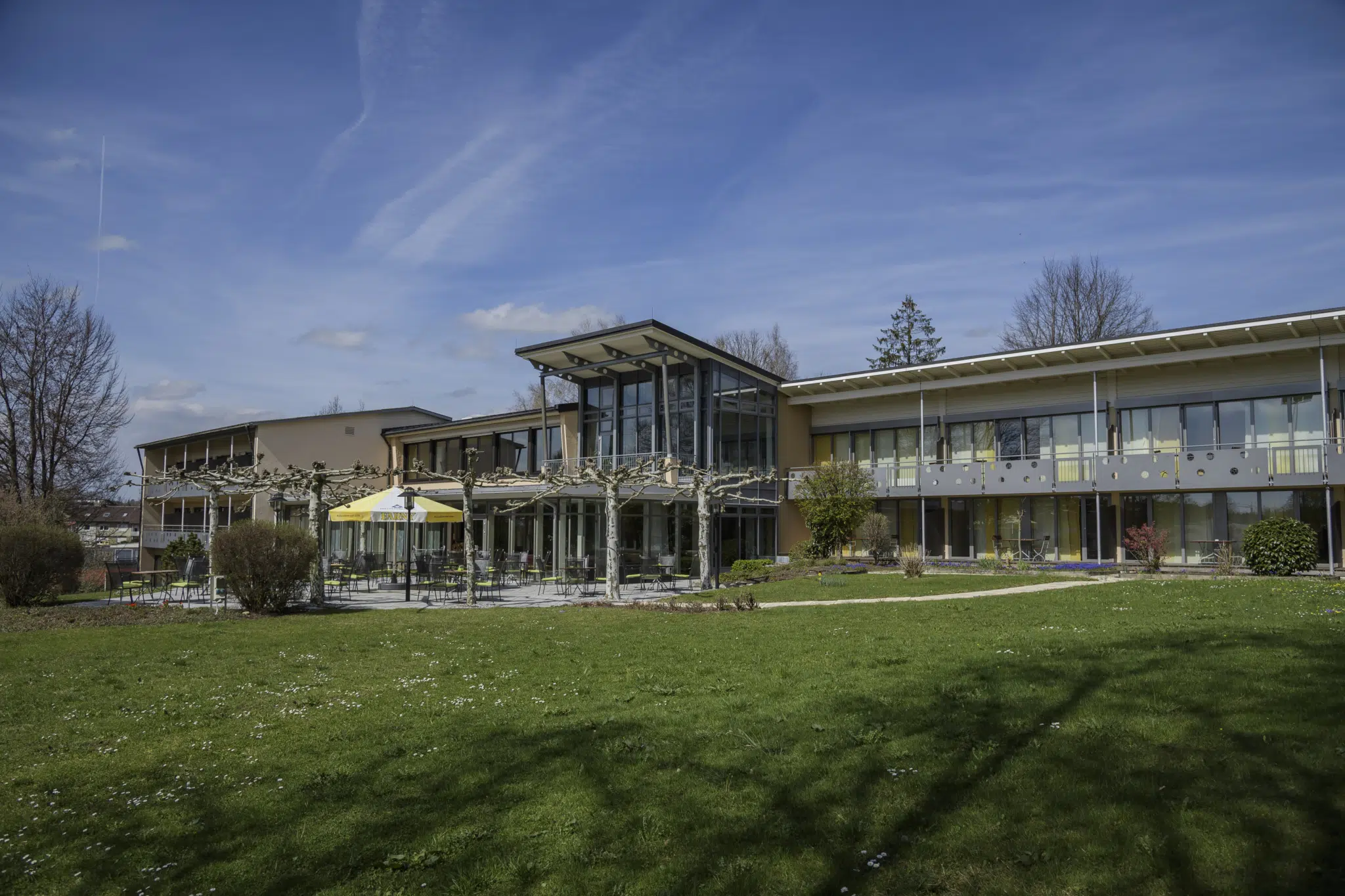 Ihr seht eine Aussenansicht mit grüner Wiese im Sommer vom JUFA Hotel Wangen im Allgäu***s. Der Ort für erfolgreiches Training in ungezwungener Atmosphäre für Vereine und Teams.