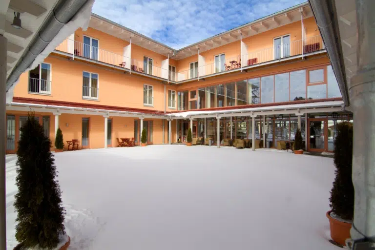 Ihr seht den schneebedeckten Innenhof vom JUFA Familienresort Kempten***s. Der Ort für kinderfreundlichen und erlebnisreichen Urlaub für die ganze Familie.