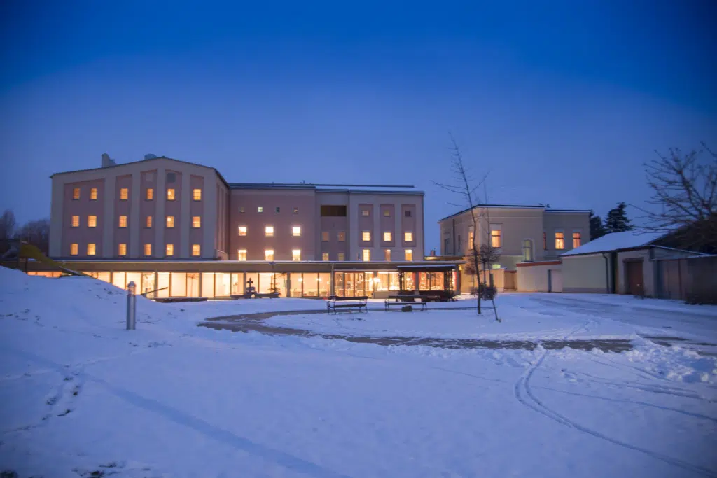 Ihre seht eine Außenansicht vom JUFA Weinviertel - Hotel zur Eselsmühle bei Abendstimmung im Winter. JUFA Hotels bietet erholsamen Familienurlaub und einen unvergesslichen Winterurlaub.