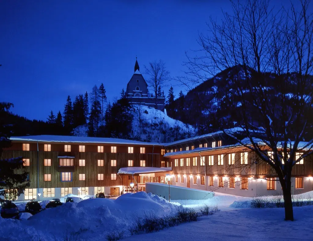 Ihr seht die Außenansicht bei winterlicher Abendstimmung vom JUFA Hotel Mariazell***. Der Ort für erholsamen Familienurlaub und einen unvergesslichen Winter- und Wanderurlaub.