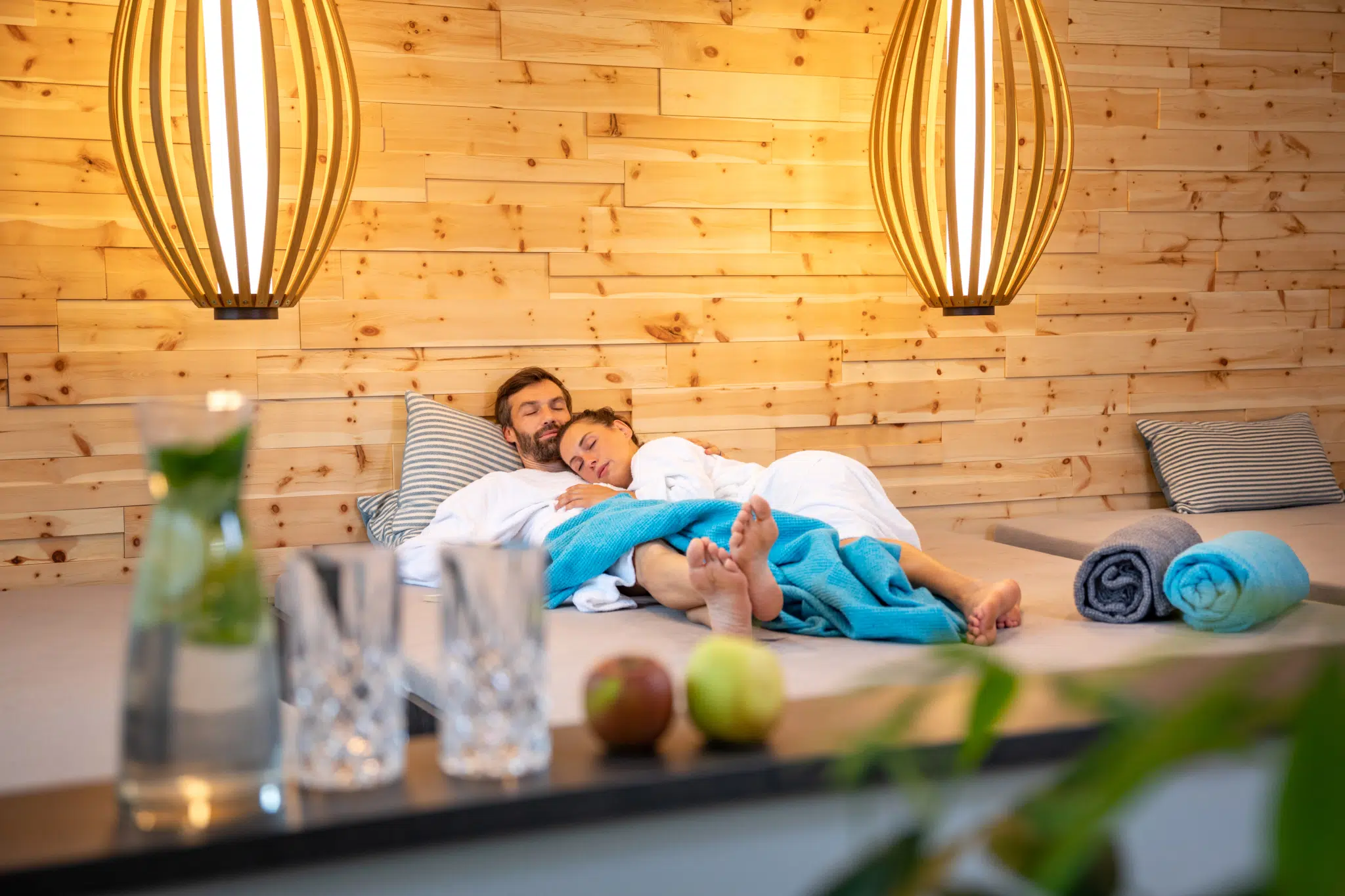 Sie sehen ein Paar, das sich im Ruhebereich der Wellnessanlage des JUFA Alpenhotel Saalbach**** entspannt. JUFA Hotels bietet erholsamen Familienurlaub und einen unvergesslichen Winter- und Wanderurlaub.