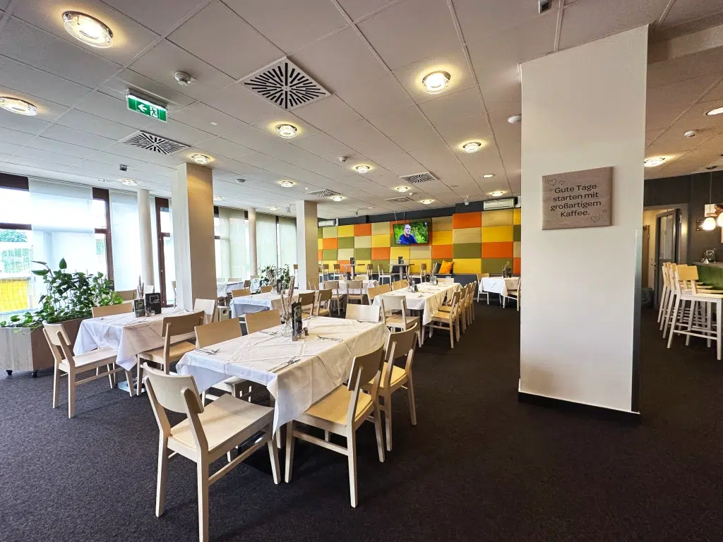 Ihr seht das Restaurant des JUFA Hotel Graz Süd mit gedeckten Tischen. Der Ort für erlebnisreichen Städtetrip für die ganze Familie und der ideale Platz für euer Seminar.