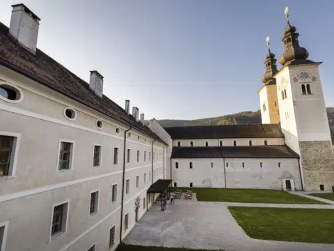 Ihr seht das JUFA Hotel Stift Gurk in der Morgensonne. Der Ort für erholsamen Familienurlaub und einen unvergesslichen Winter- und Wanderurlaub.