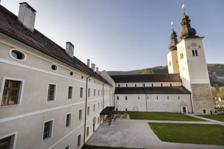 Ihr seht das JUFA Hotel Stift Gurk in der Morgensonne. Der Ort für erholsamen Familienurlaub und einen unvergesslichen Winter- und Wanderurlaub.