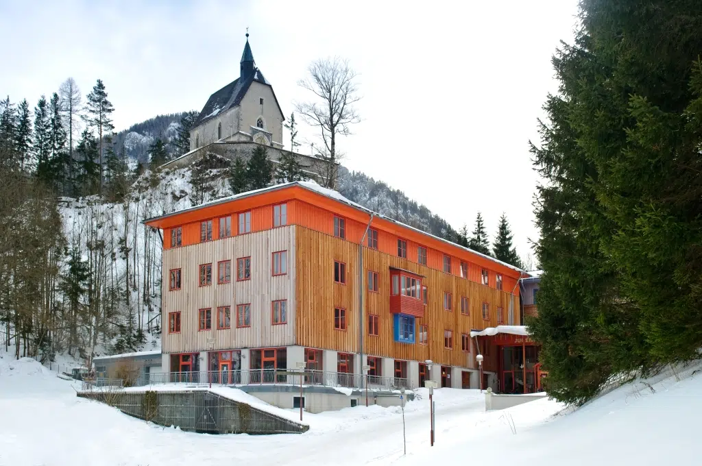 Ihr seht die Außenansicht in winterlicher Stimmung vom JUFA Hotel Mariazell***. Der Ort für erholsamen Familienurlaub und einen unvergesslichen Winter- und Wanderurlaub.