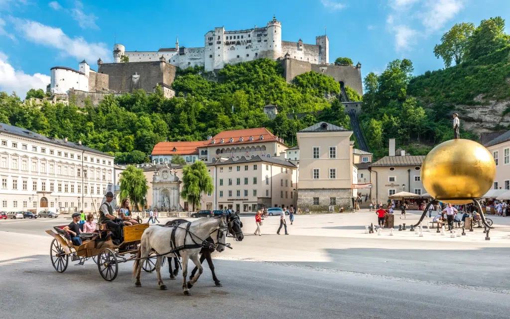 Ihr seht den Kapitelplatz in Salzburg mit Fiaker und Blick auf die Festung.