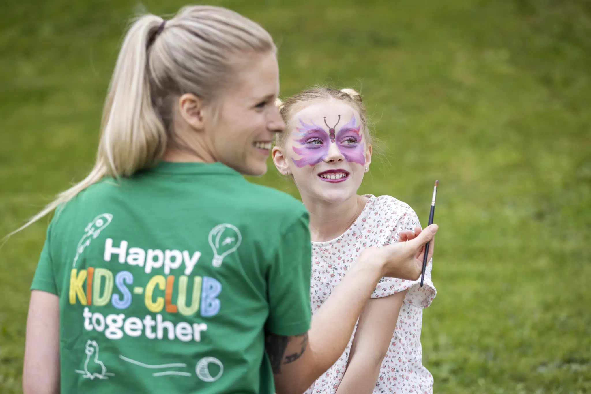 Ihr seht eine Kids-Club Betreuerin der JUFA Hotels, die ien Kind als Schmetterling schminkt.