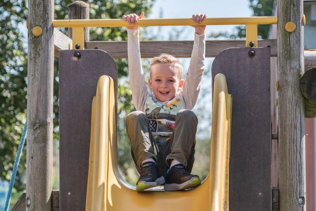 Ihr seht ein Kind auf einer gelben Rutsche. JUFA Hotels bietet kinderfreundlichen und erlebnisreichen Urlaub für die ganze Familie.