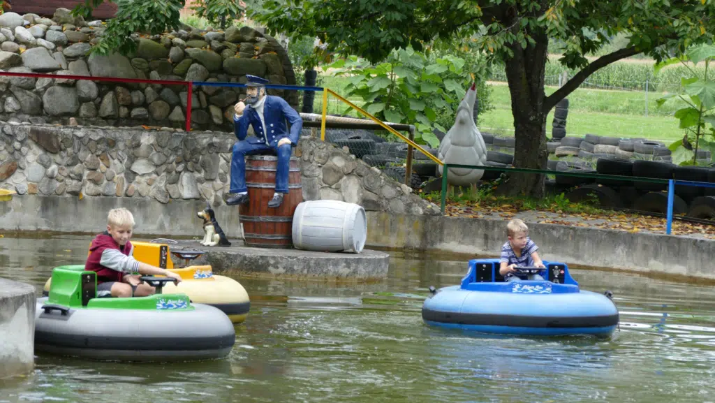 Zwei Jungen fahren auf Elektrobooten im Freizeitpark Stubenbergsee JUFA Hotels bieten erholsamen Familienurlaub und einen unvergesslichen Winter- und Wanderurlaub.