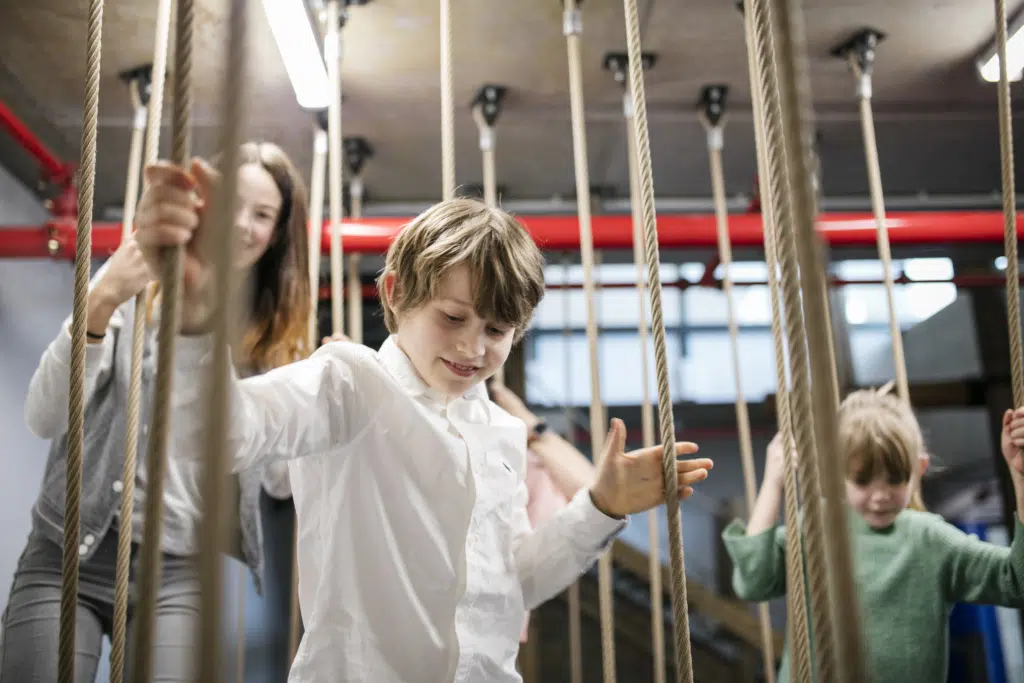 Ihr seht Kinder beim Klettern im Indoor-Spielbereich des JUFA Hotels Hamburg HafenCity****. Der Ort für kinderfreundlichen und erlebnisreichen Urlaub für die ganze Familie.