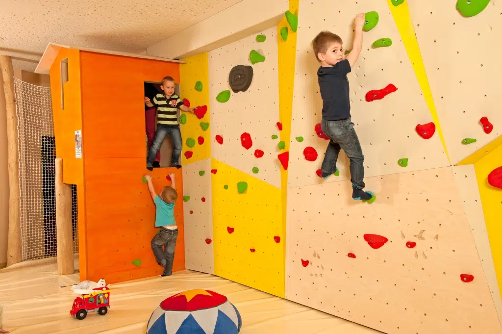 Kind klettert an der Kletterwand im Spielbereich des JUFA Hotel Grünau im Almtal. Der Ort für erholsamen Familienurlaub und einen unvergesslichen Winter- und Wanderurlaub.