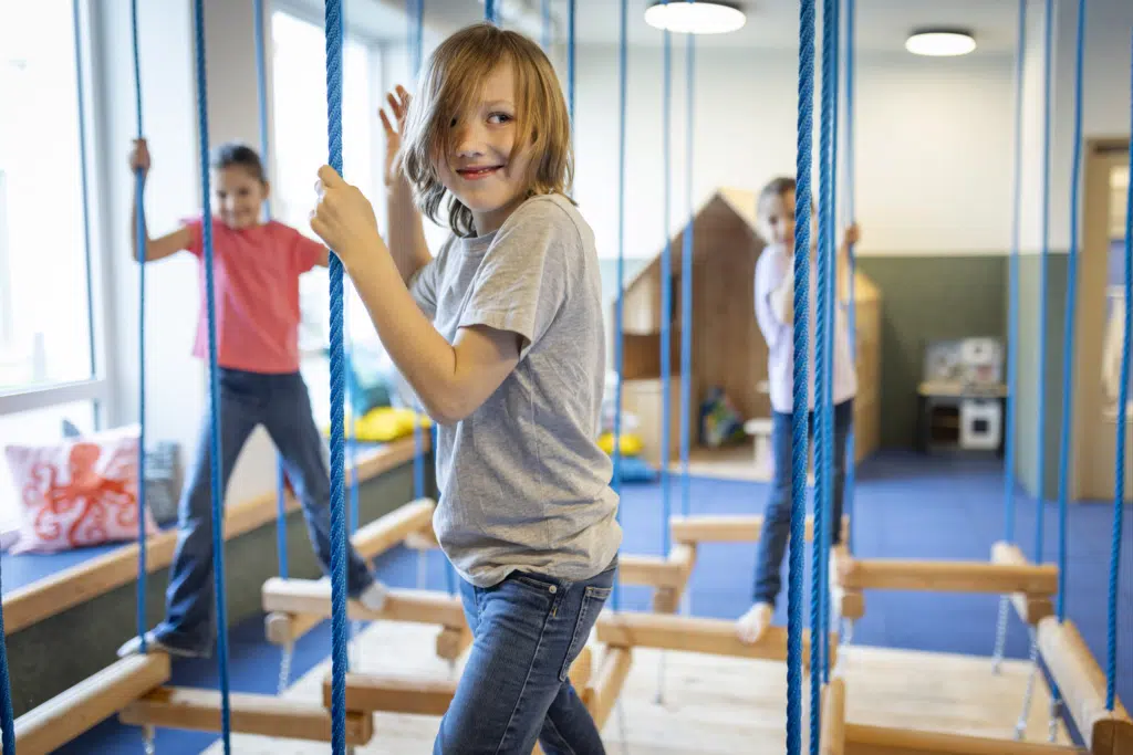 Ihr seht lachende KInder auf dem Motorikparcours aus Holz ud Seilen im Indoor-Kinderspielbereich im JUFA Hotel Bad Radkersburg