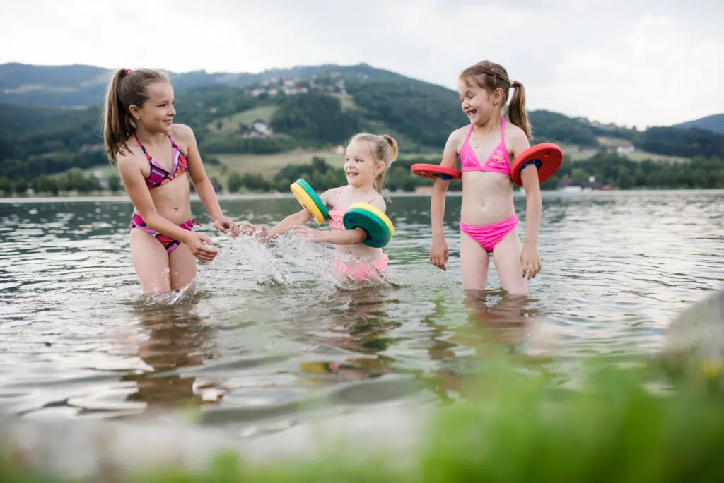 Ihr seht Kinder im Stubenbergsee im Sommer. JUFA Hotels bietet tollen Sommerurlaub an schönen Seen für die ganze Familie.