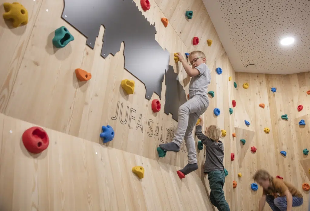 Ihr seht Kinder beim Klettern im Spielbereich im JUFA Hotel Salzburg City. Der Ort für erholsamen Familienurlaub und einen unvergesslichen Winter- und Wanderurlaub.